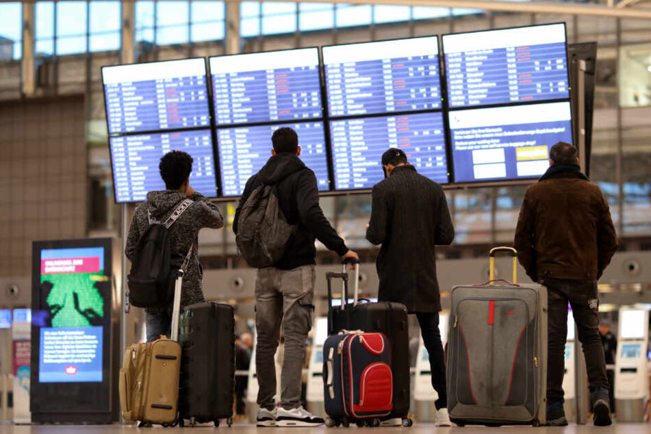 Fluggäste checken ihre Flüge an einer Anzeigetafel im Flughafen Hamburg.