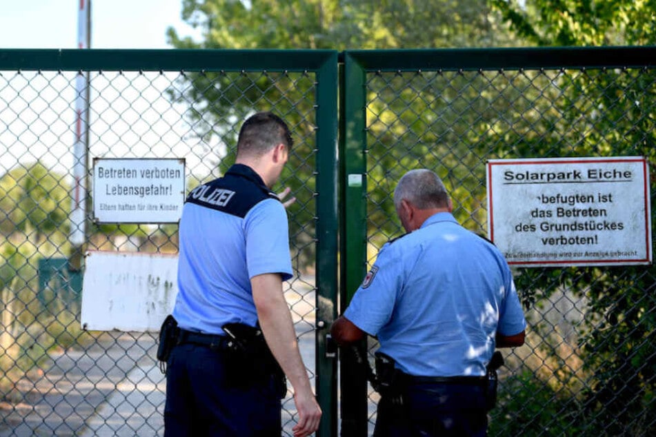 Polizisten schließen das Tor zum Gelände, auf dem die Leiche gefunden wurde.