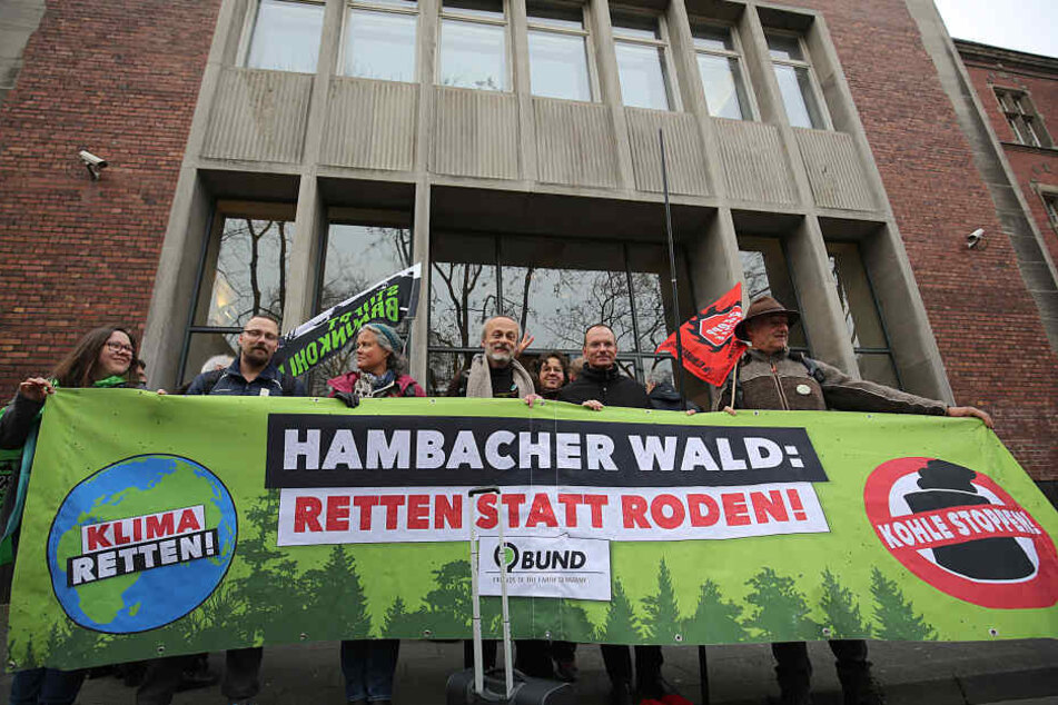 Umweltaktivisten und Braunkohlegegener stehen mit einem Transparent vor dem Verwaltungsgericht.