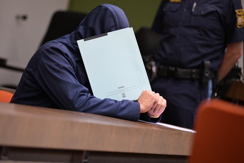 Der Angeklagte im Prozess wegen versuchten Mordes versucht, sein Gesicht zu verdecken.