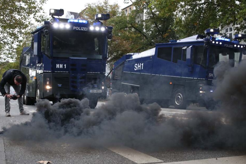Eine Rauchbombe qualmt vor den Einsatzwagen der Hamburger Polizei beim Fan-Marsch der HSV-Anhänger zum Derby beim FC St. Pauli.