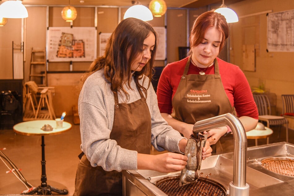 Produktionsleiterin Sofia Zarko (26, r.) zeigt Gästin Lena Pätzold (23), wie die flüssige Schokolade in die Bärenform kommt.