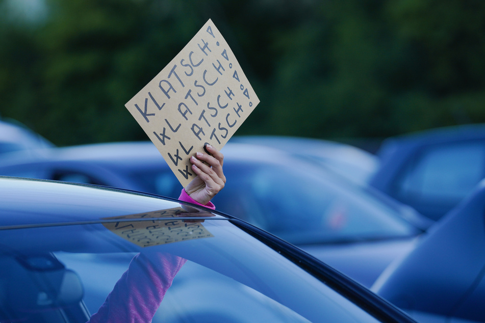 Eine Zuschauerin hält bei einem Auftritt des Comedian Bülent Ceylan im Autokino beim "Car-watch-Festival" mit seinem Programm "OPEN hAIR SPEZIAL" ein Plakat mit der Aufschrift "Klatsch! Klatsch! Klatsch! Klatsch!" aus dem Autofenster.