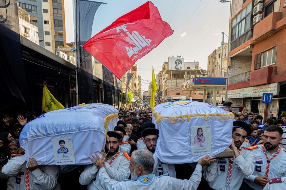 Scouts carry the coffins of two children, Hassan and Amira Muhammed Fadallah, during their funeral a day after they were killed in an Israeli strike on a building in Beirut's southern suburbs, on July 31, 2024.