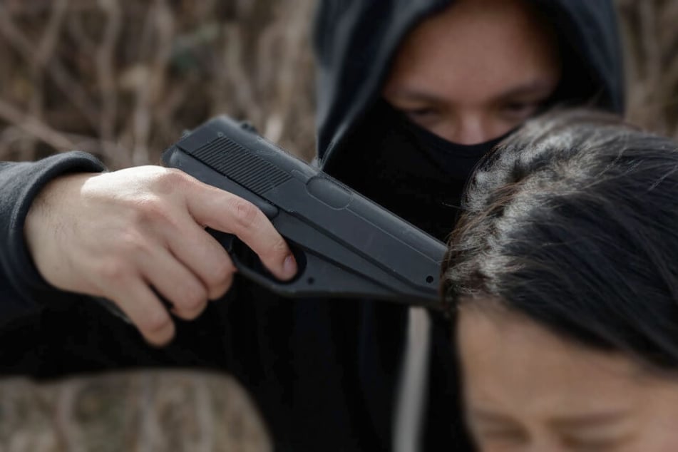 Mann drückt Frau Waffe an den Kopf und bedroht sie. (Symbolbild)