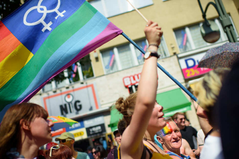 Teilnehmerin ziehen mit einer Regenbogenfahne durch die Stadt.
