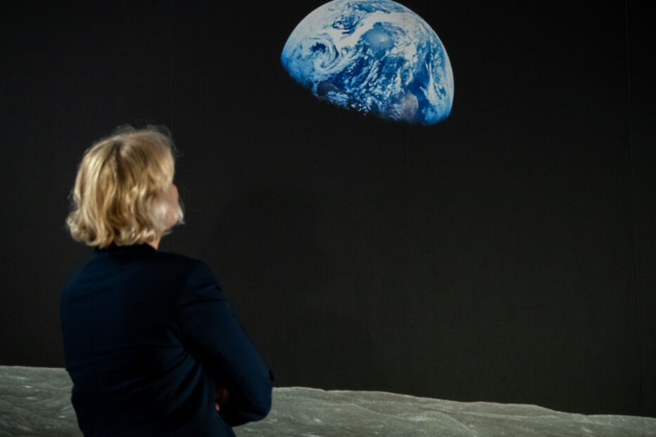 Eine Frau betrachet während der Ausstellung das aus der Apollo 8 aufgenomme Bild "Earthrise".