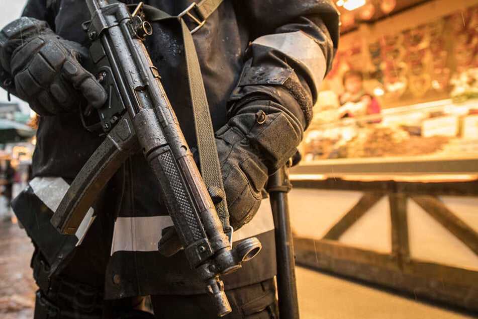 Mit einer Maschinenpistole bewaffneter Polizist auf einem Weihnachtsmarkt.