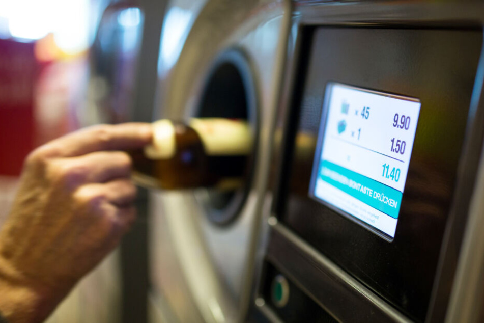 Ein Flaschensammler wirft eine Funde in einen Automaten.