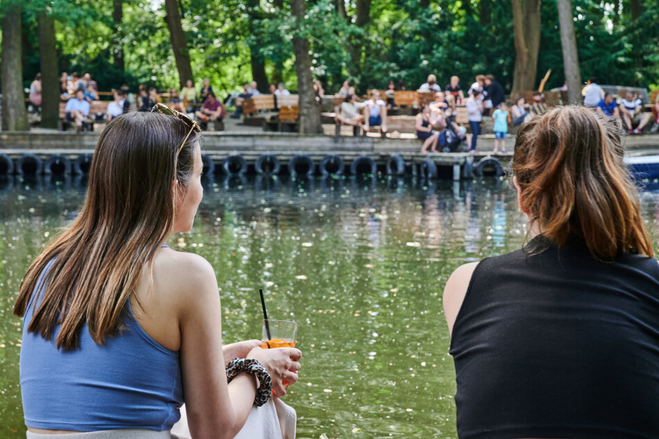 Zwei Frauen sitzen am Wasser im Cafe am Neuen See und genießen das gute Wetter.