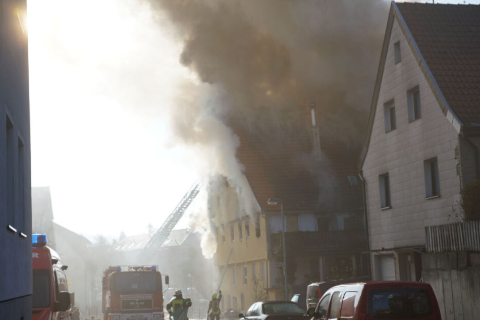 Die Feuerwehr löscht die Flammen, die aus dem Haus schlagen.