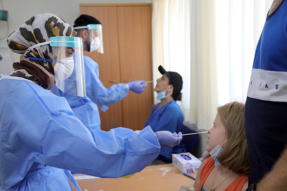 Mediziner in Schutzkleidung, mit Mundschutz und Schutzschild vor den Gesichtern entnehmen zwei Personen Proben, um sie auf das Coronavirus zu testen. Möglicherweise können wir das bald zu Hause selbst machen. (Archivbild)