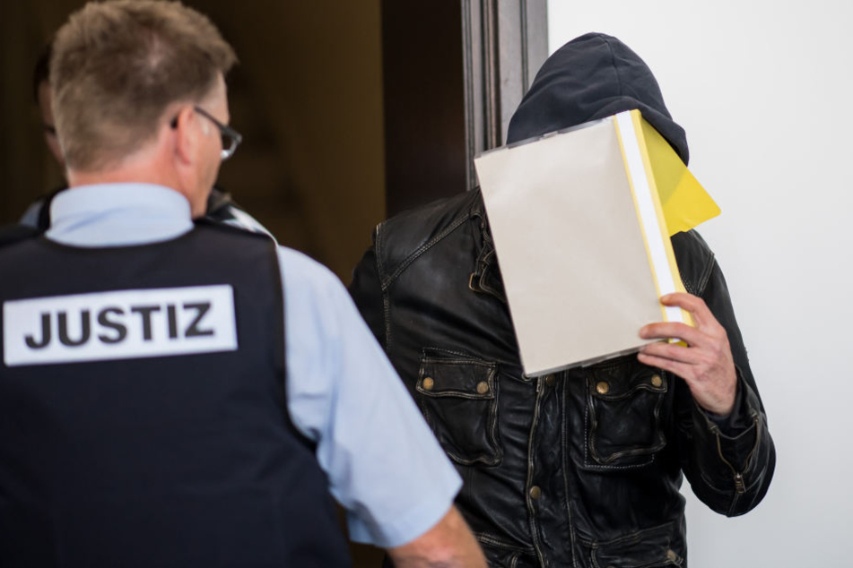 Er verdeckt sein Gesicht mit einem Schnellhefter.