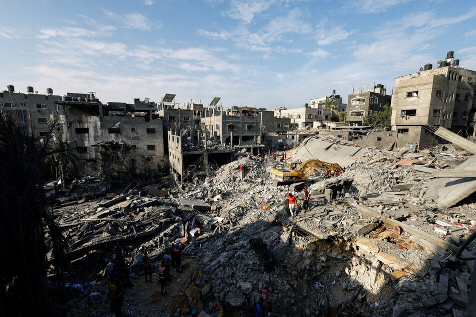 Emergency personnel work at the site of Israeli strikes on houses in Khan Younis in the southern Gaza Strip on October 27, 2023.