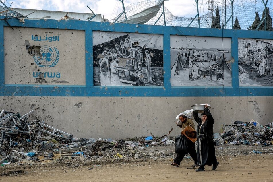 Palestinian people walk past the Gaza City headquarters of UNRWA, heavily damaged in Israeli bombing.