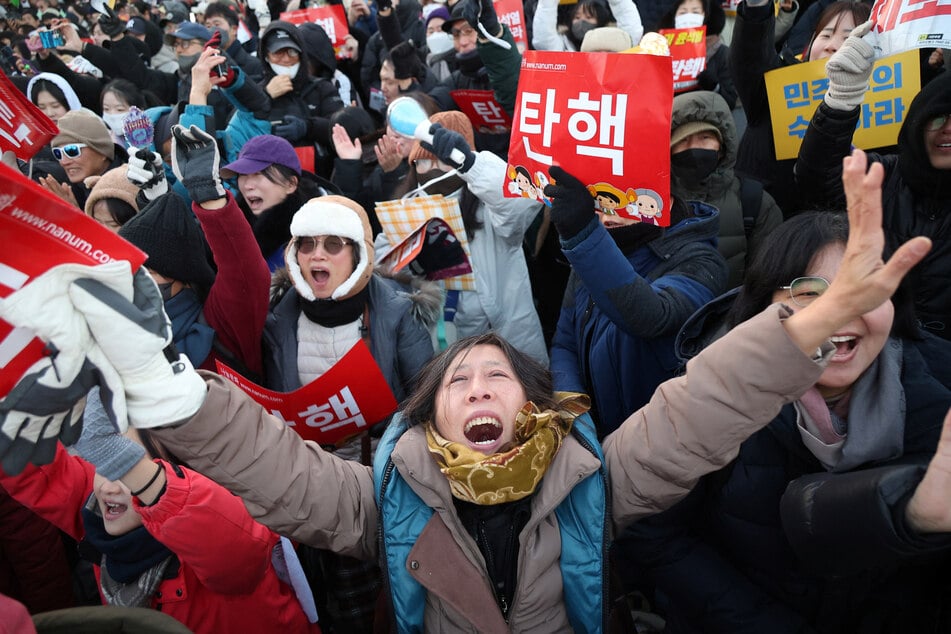 People in Seoul celebrate after South Korean parliament passed a second impeachment motion against President Yoon Suk Yeol over his martial law decree.