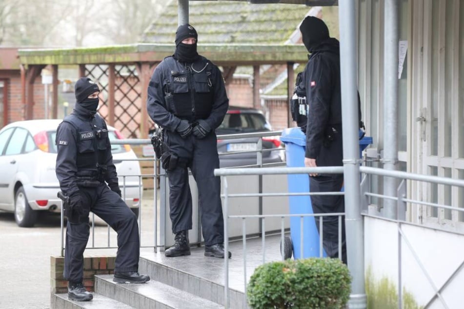 Einsatzkräfte der Polizei stehen während einer Durchsuchung vor einem Haus im Kreis Dithmarschen.