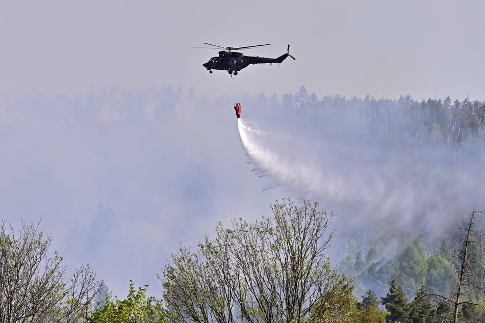 Ein Hubschrauber bekämpft mit einem Löschwasser-Behälter einen Waldbrand bei Rynartice im Nationalpark Böhmische Schweiz.