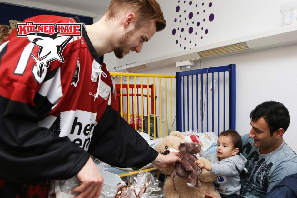 Lucas Dumont (21) von den Kölner Haien beschenkt einen jungen Patienten im Kinderkrankenhaus.