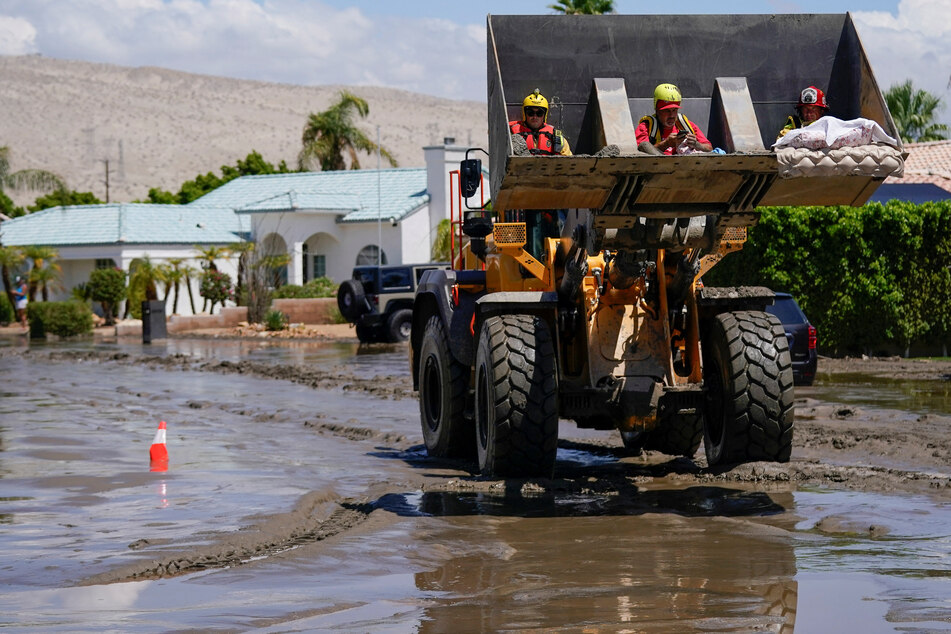Firefighters use construction equipment to transport residents who had been trapped in their homes to waiting ambulances following Tropical Storm Hilary in Cathedral City, California.