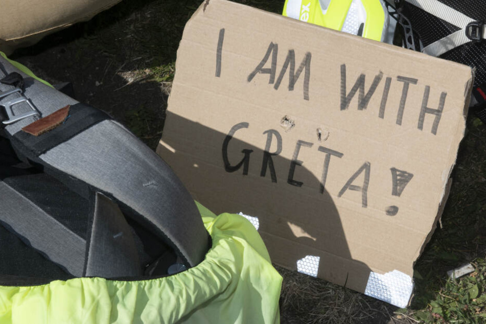 Ein Schild mit der Aufschrift "I am with Greta" liegt neben einem Rucksack.
