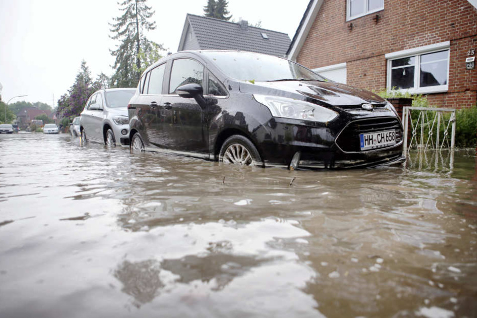 Autos stehen auf einer Überfluteten Straße in Hamburg-Bergedorf.