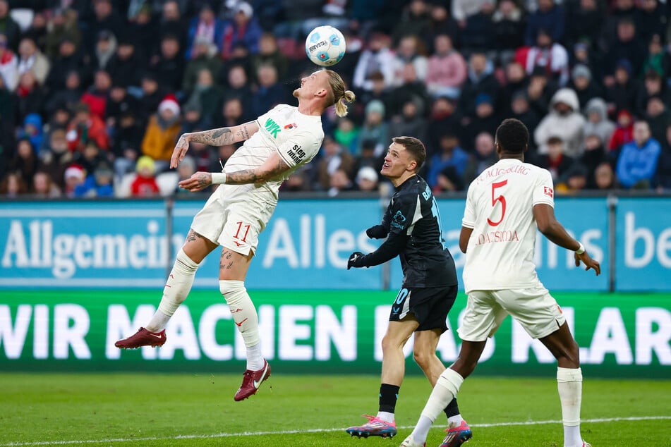 Augsburgs Marius Wolf (l.) hatte trotz intensivem Auftreten spielerisch keine Chance gegen die Leverkusener um Florian Wirtz (Mitte).