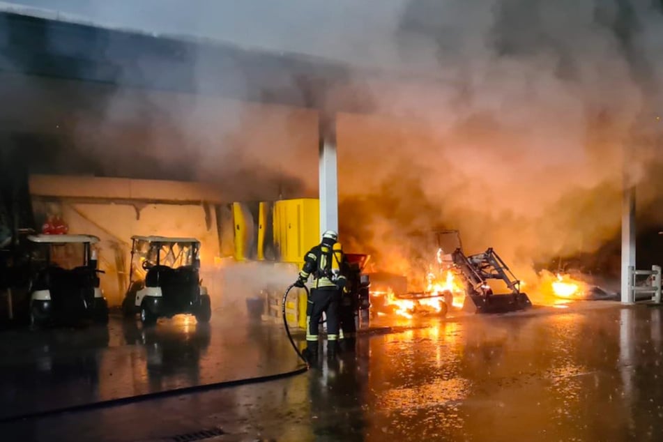 Einsatzkräfte der Feuerwehr kämpfen gegen die Flammen, die sich über den Fuhrpark hermachen.