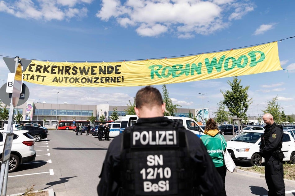 Polizisten sichern eine Aktion von Aktivisten der Naturschutzorganisation Robin Wood auf dem Tesla-Parkplatz in Grünheide.