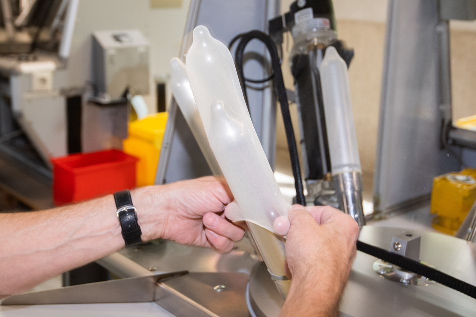 Ein Mitarbeiter zieht Kondome auf eine Metallvorrichtung bei der Überprüfung einer Stichprobe während der Qualitätskontrolle. Alle anderen Kondome werden elektronisch überprüft.