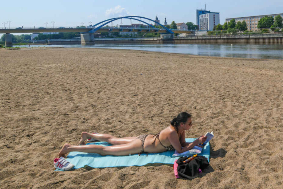 Wo sonst die Oder fließt, sonnt sich eine Frau auf der polnischen Uferseite auf einer großen Sandbank. 