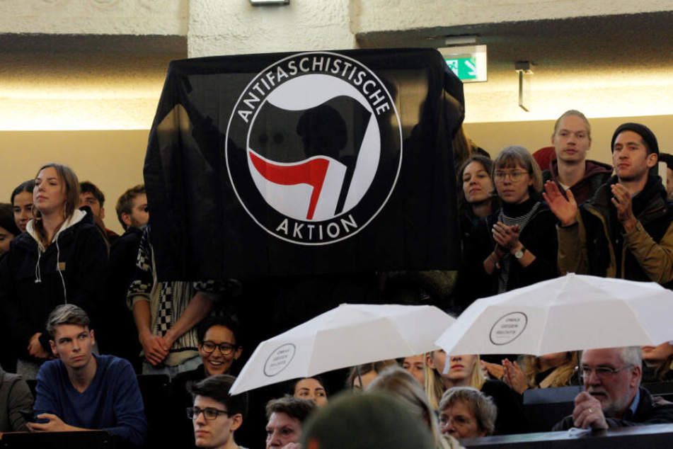 Demonstranten halten im Hörsaal der Uni Hamburg eine Fahne der Antifa hoch.