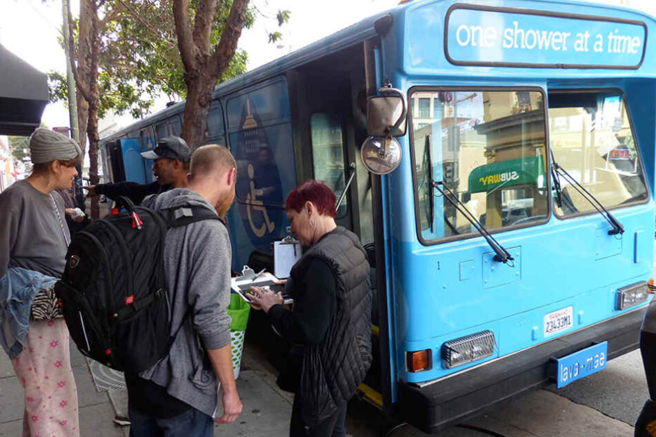 Obdachlose werden in San Francisco in die Warteliste für den mobilen Dusch-Bus mit der Aufschrift "One Shower at a Time" eingetragen.