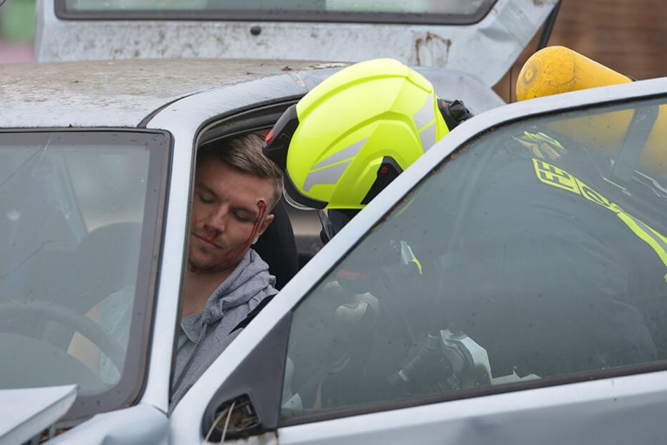 Eine Person ist scheinbar schwer verletzt im Fahrzeug eingeklemmt und muss von Rettungskräften geborgen werden.