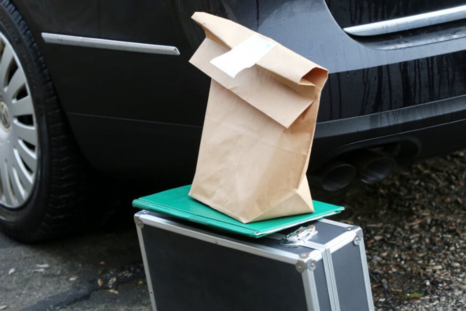 Beweismittel stehen auf einem Koffer mit einer Akte neben einem Auto des Bundeskriminalamtes.