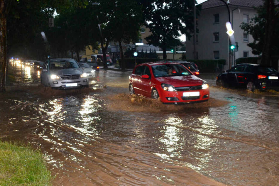 Autos fahren nach einem schweren Unwetter über eine überflutete Straße bei Heilbronn.