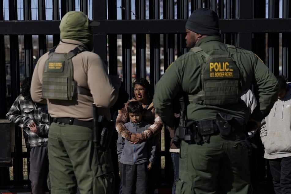 US Border Patrol agents stand guard as migrants who crossed into Shelby Park wait to be picked up for processing in Eagle Pass, Texas.