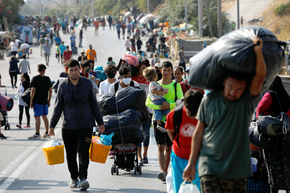 Migranten tragen ihre Habseligkeiten auf einer Straße, die von Moria nach Mytilini führt.