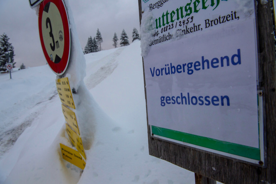 Ein Hinweisschild auf einen Gasthof mit der Aufschrift "Vorübergehend geschlossen" steht neben einem Weg im Skigebiet Kranzberg oberhalb von Mittenwald.