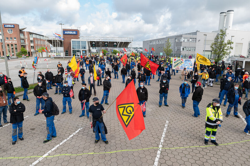 Beschäftigte des Airbus-Werkes in Hamburg-Finkenwerder stehen vor den Toren des Werksgeländes: Es droht ein neuer Warnstreik. (Archivbild)