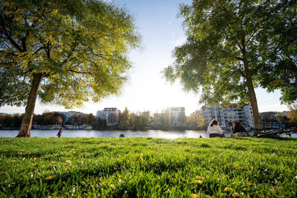 Menschen genießen die milden Herbst-Temperaturen im Sonnenschein an der Spree.