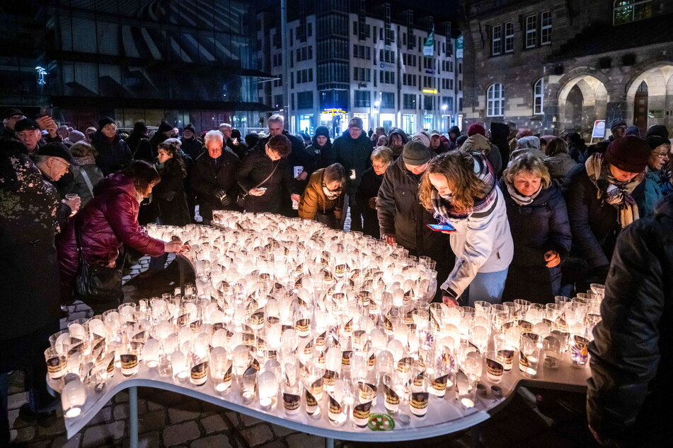 Besucher des Chemnitzer Friedenstags 2023 stellten am Abend Lichter auf eine Friedenstaube auf dem Neumarkt.
