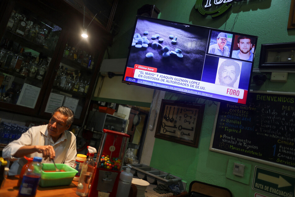 A barman stands next to a TV showing the news of the arrest of Mexican drug lord Ismael "El Mayo" Zambada and the son of his former partner, Joaquin "El Chapo" Guzman, at a cantina in Mexico City.