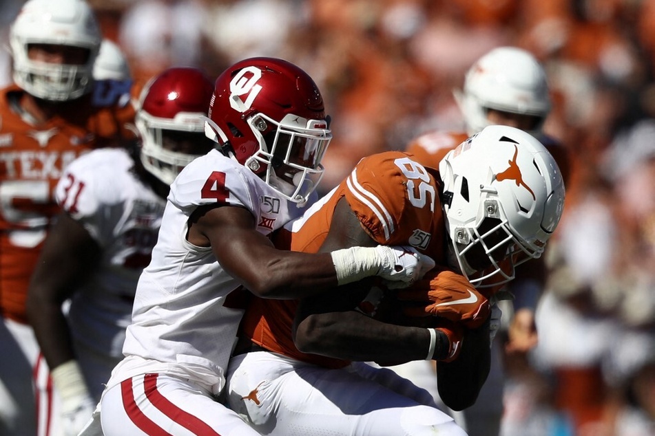 Malcolm Epps of the Texas Longhorns is tackled by Jaden Davis of the Oklahoma Sooners during the 2019 AT&amp;T Red River Showdown at the Cotton Bowl.
