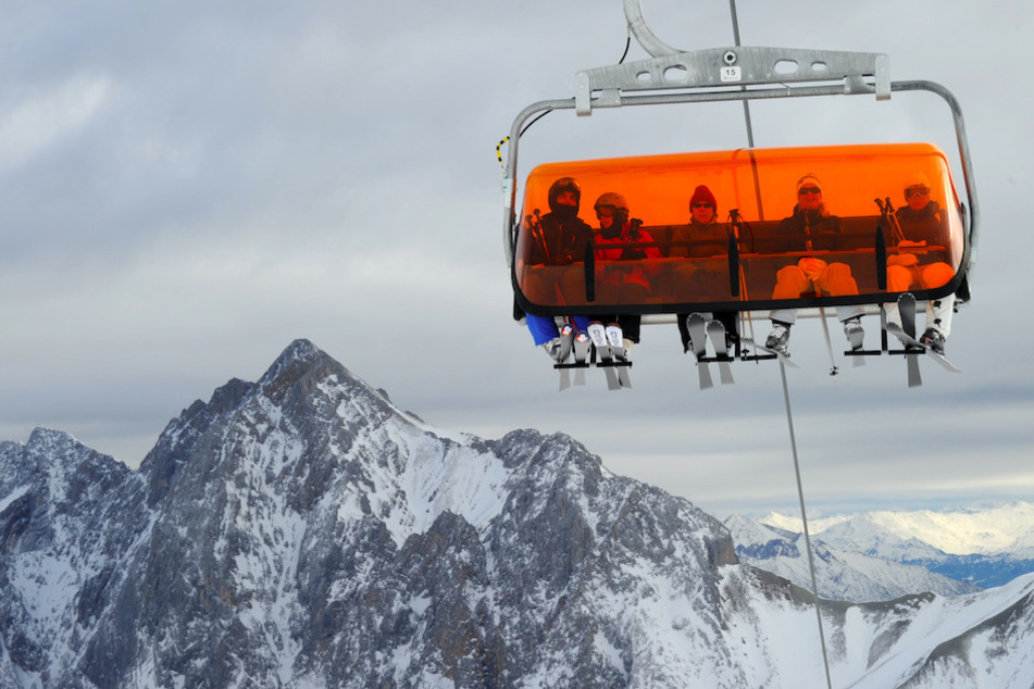 Skifahrer sitzen im Skigebiet der Zugspitze bei Garmisch-Partenkirchen in einem Sesselllift.