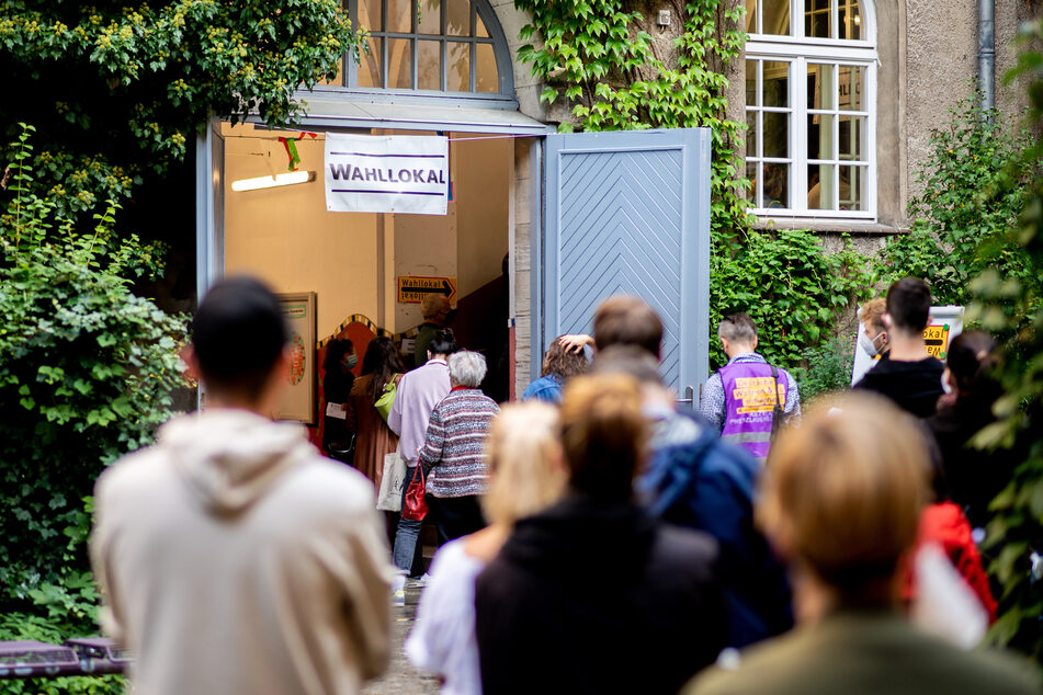 Etliche Menschen stehen z. B. in Prenzlauer Berg vor einem Wahllokal an, um ihre Stimmen abzugeben.