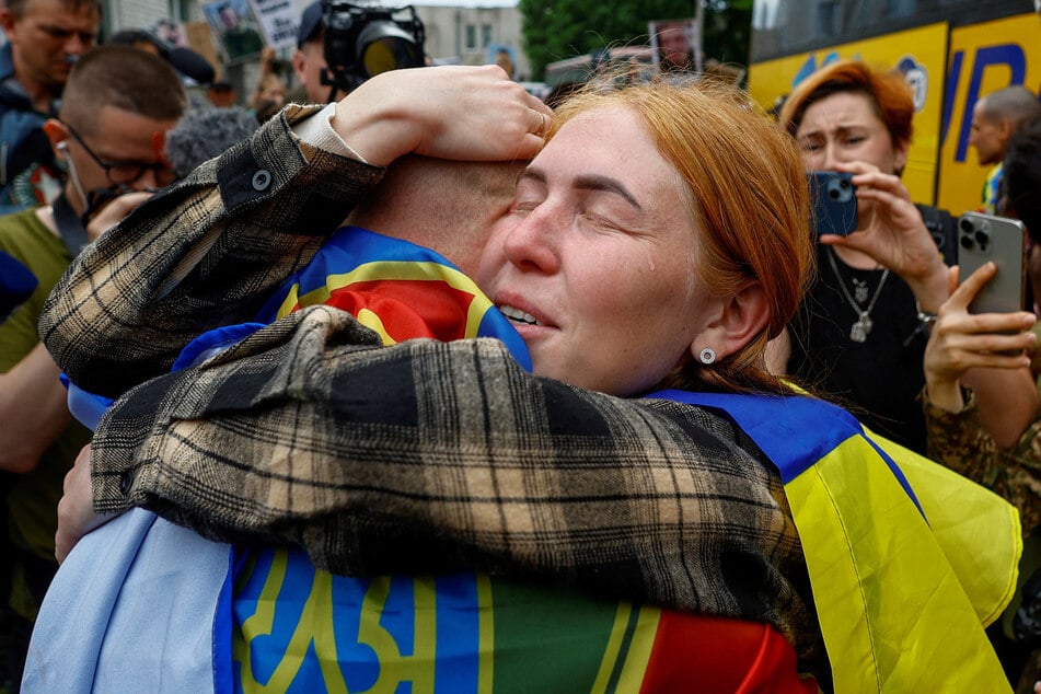 A woman reacts as she embraces her husband, a Ukrainian prisoner of war who returns after a swap on May 25, 2025.