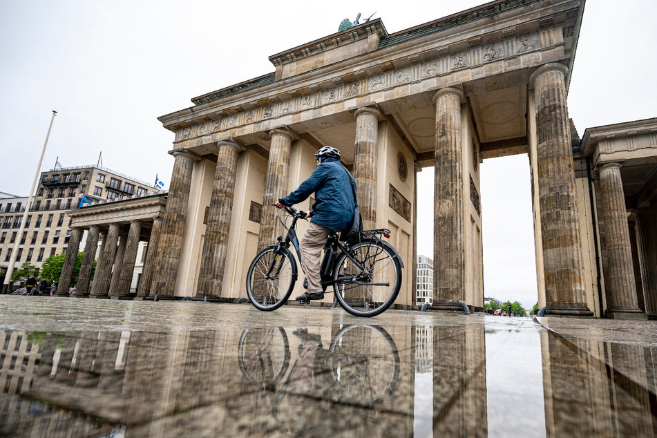 Ein Mann fährt auf seinem Fahrrad am Brandenburger Tor vorbei. Auch zum Ende der Woche könnte es in der Hauptstadt nass werden.