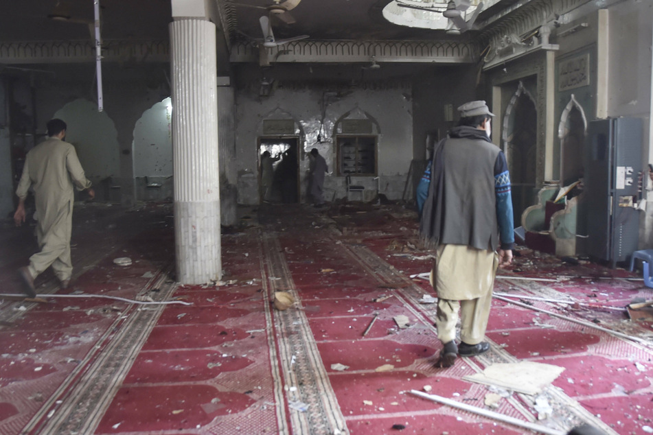 People inspect the damaged area of a mosque following a blast in Peshawar, Pakistan, on March 4, 2022.