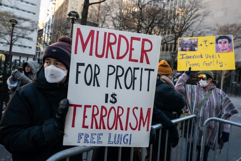 Protestors hold signs outside of Manhattan Criminal Court on December 23, 2024, as Luigi Mangione was set to appear for arraignment on state murder charges in the killing of UnitedHealthcare CEO Brian Thompson.